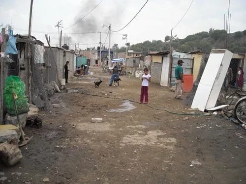 Asentamiento irregular en México con viviendas precarias, piso de tierra y servicios públicos limitados